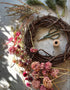 A grapevine wreath base with dried garden stems, twine, and scissors